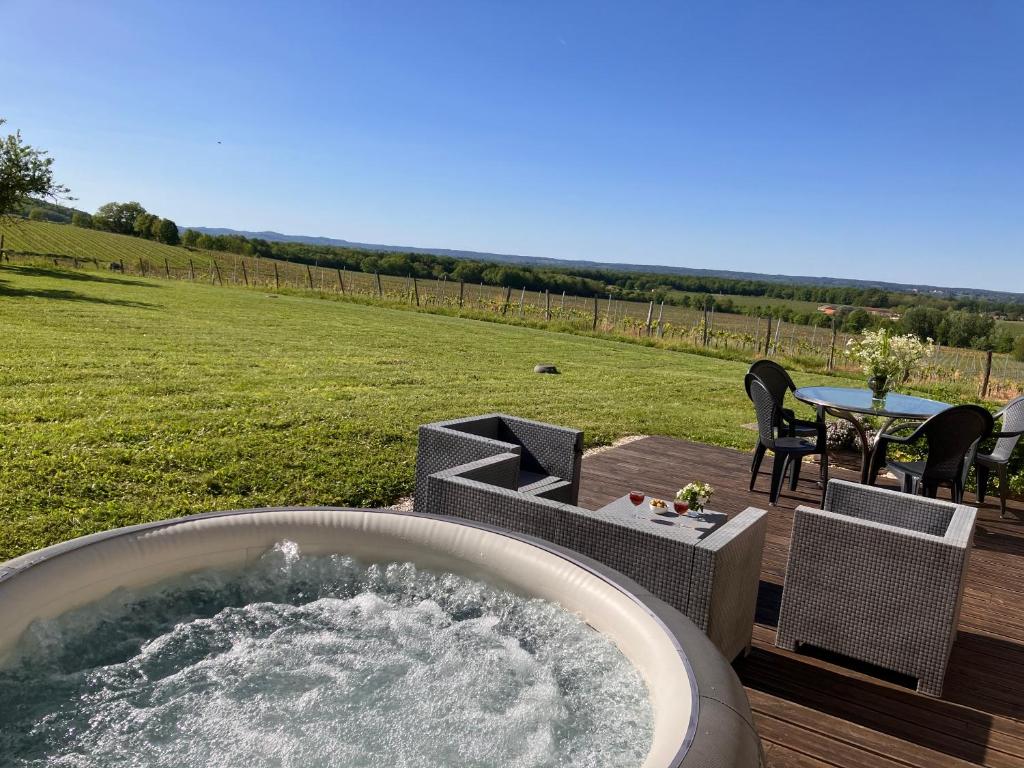 - un bain à remous sur une terrasse avec une table et des chaises dans l'établissement Périgourdine avec spa et vue, à Pomport