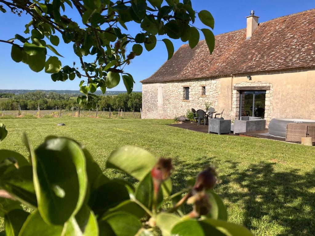 a large stone building with a grassy yard at Périgourdine avec spa et vue in Pomport