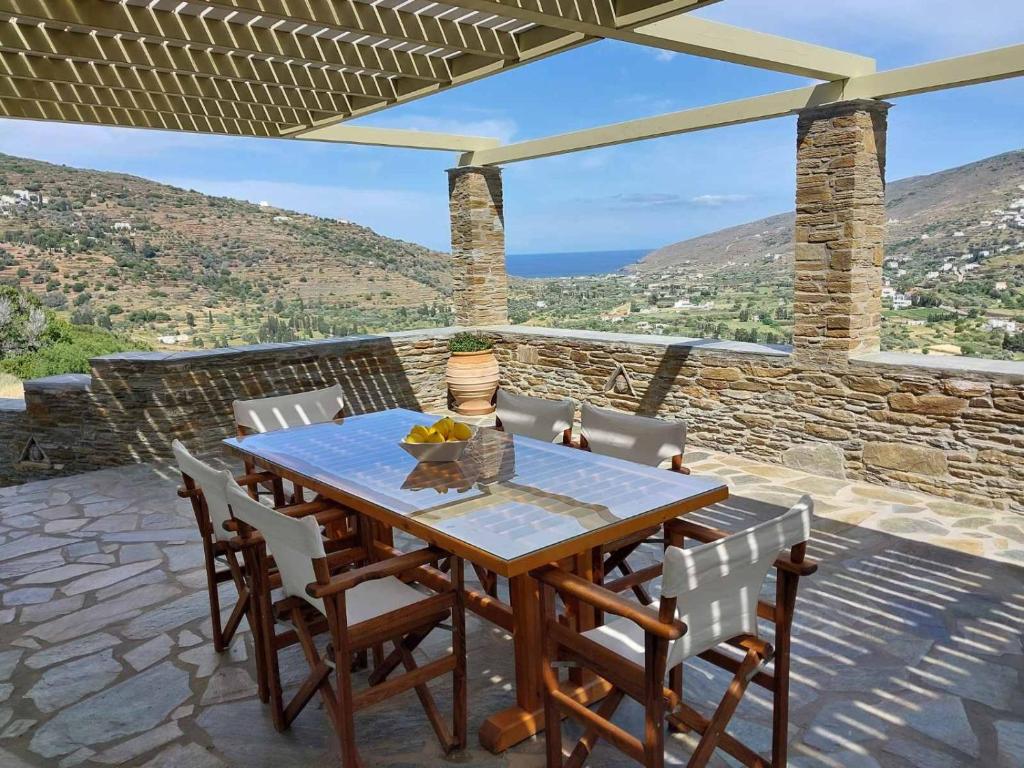 a wooden table and chairs on a patio with a view at Anchorage Andros Villa in Andros