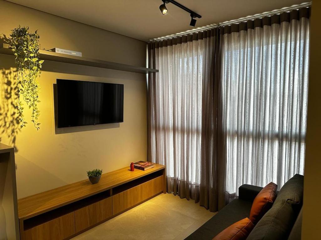 a living room with a couch and a tv and a window at PARK SUL - Edifício Essence - 4 in Brasilia