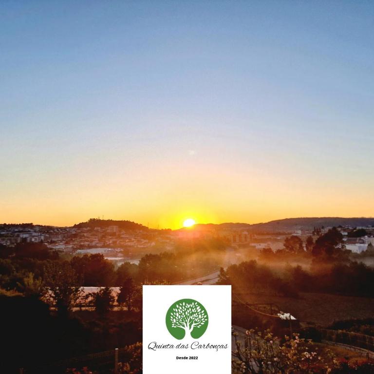 a sunset with a tree logo in the foreground at Quinta das Carbonças in Fafe