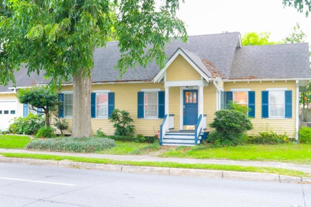 a yellow house with blue shutters and a tree at Work Crew Haven: Spacious Corporate Lodging in Lafayette
