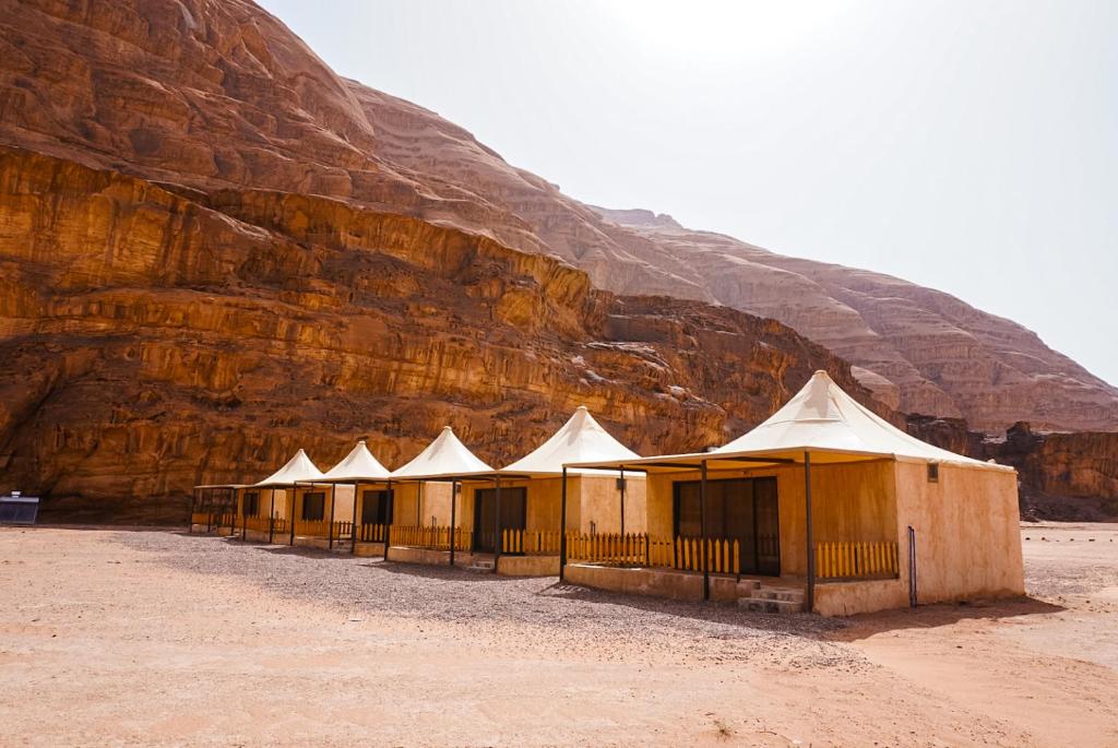 una fila de tiendas de campaña frente a una montaña en Solana Desert Camp & Tour en Wadi Rum