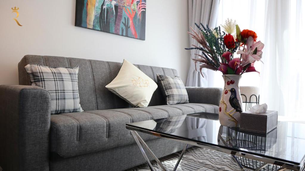 uma sala de estar com um sofá e uma mesa com um vaso de flores em Your Sleek Transit 1BR Oasis Hideaway em Abu Dhabi