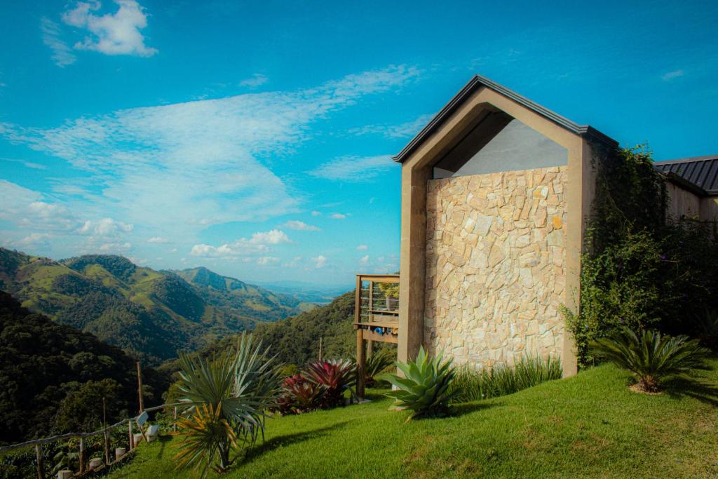 un edificio en una colina con montañas al fondo en Cabana na montanha com Ofurô ao ar livre, churrasqueira, trilha com cascata e Starlink, en Cambuí