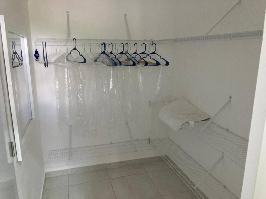 ein weißes Bad mit einer Dusche und Kleiderbügeln in der Unterkunft Beautiful With Balcony in Concepción de La Vega