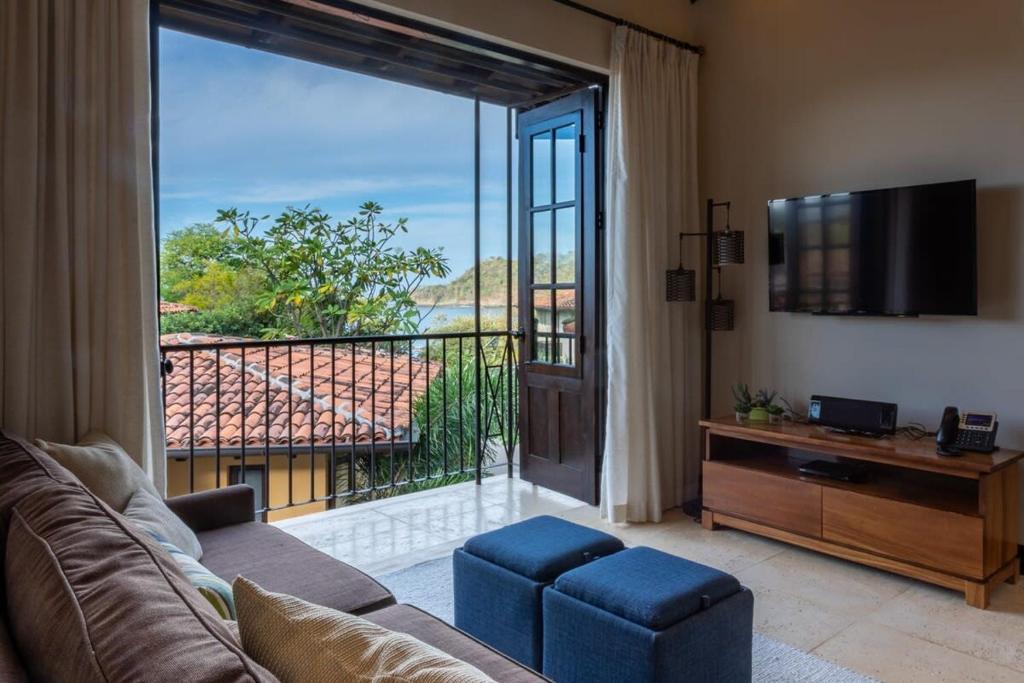 ein Wohnzimmer mit einem Sofa, einem TV und einem Balkon in der Unterkunft Beautiful Penthouse in Las Catalinas with Stunning Ocean View in Playa Danta