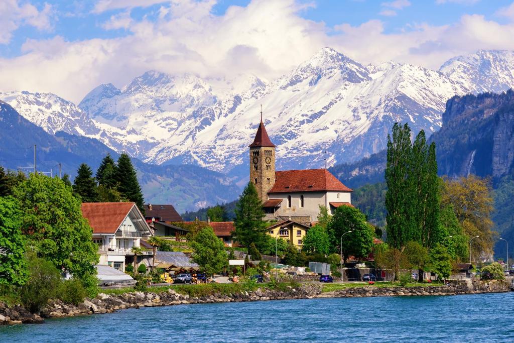 a town next to a river with snow covered mountains at Apartment am schönen Brienzersee in Brienz