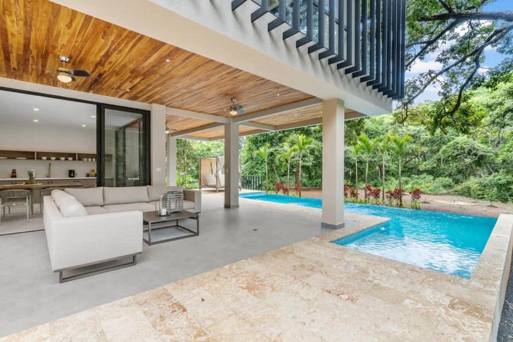 uma sala de estar exterior com um sofá branco e uma piscina em Casa Vi em Brasilito