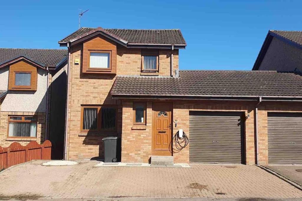 a brick house with a garage in a driveway at Sunny Cove Holiday Let in Aberdeen