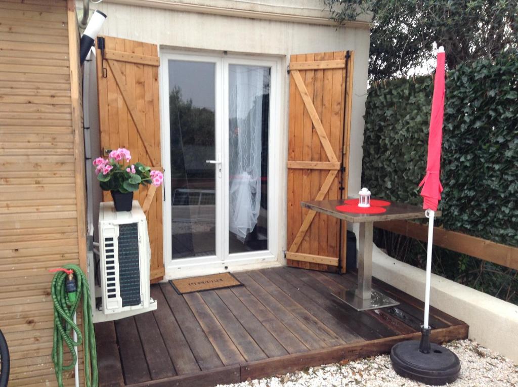 une terrasse en bois avec une porte et une table dans l'établissement la loggia, à Porto-Vecchio