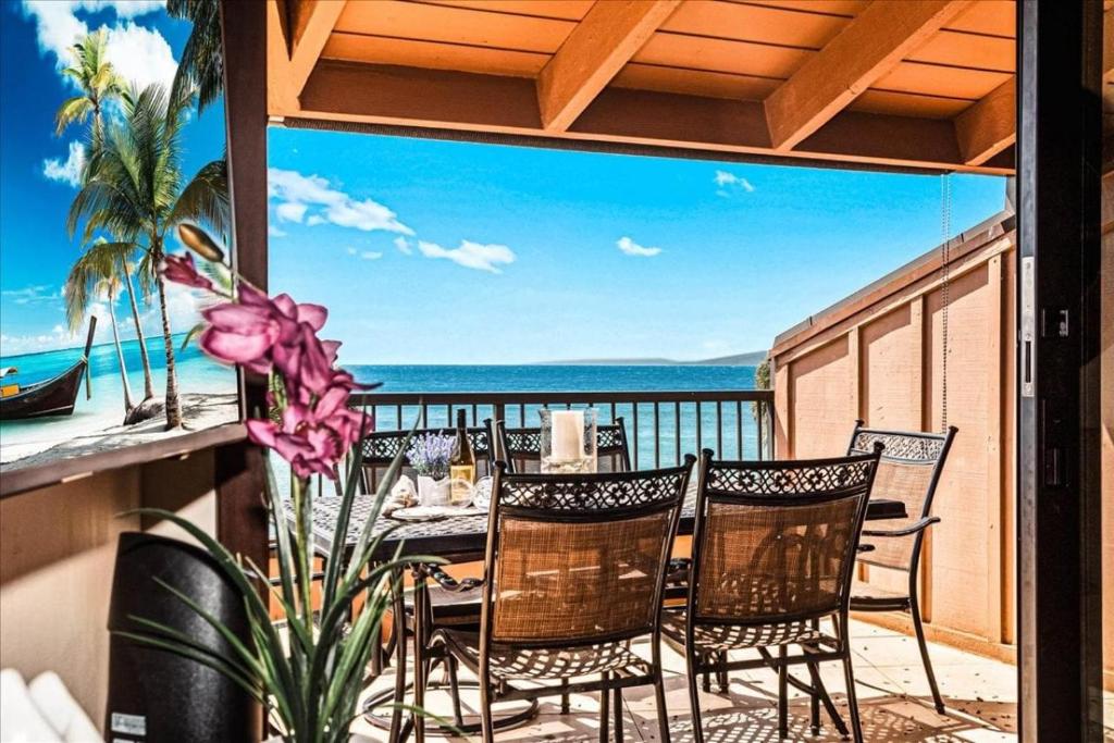 a table and chairs on a balcony with a view of the ocean at Kuleana Resort 104 in Kahana