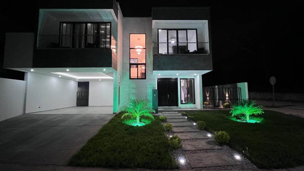 een huis met twee planten er 's nachts voor bij DaVinciHouse in San Pedro Sula