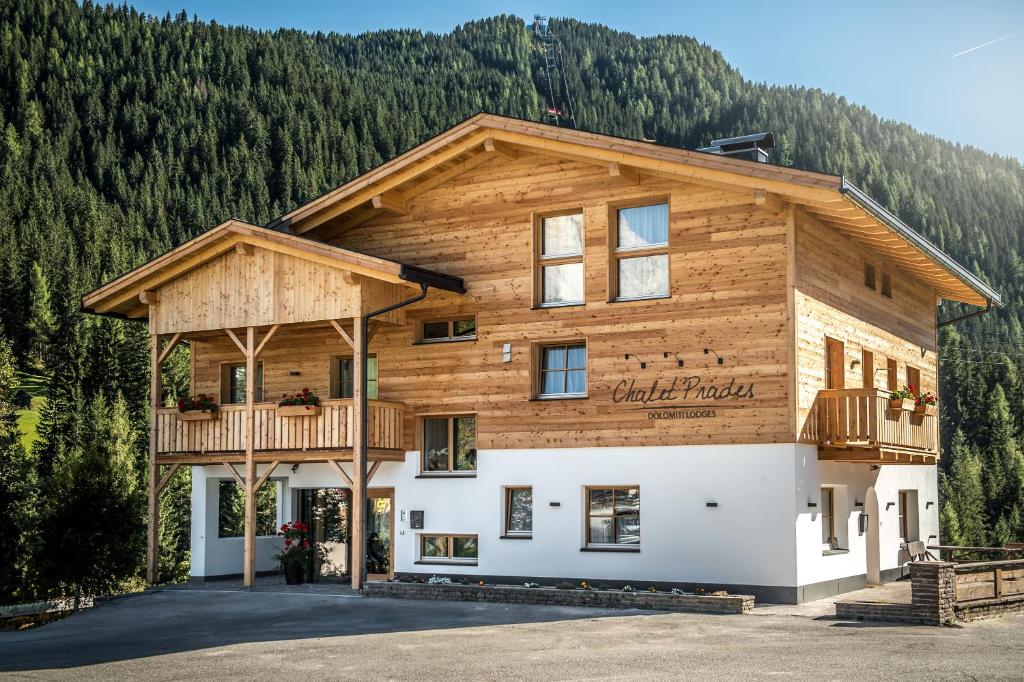 Chalet Prades Dolomiti Lodges في لا فيلا: منزل خشبي مع شرفة على الجانب