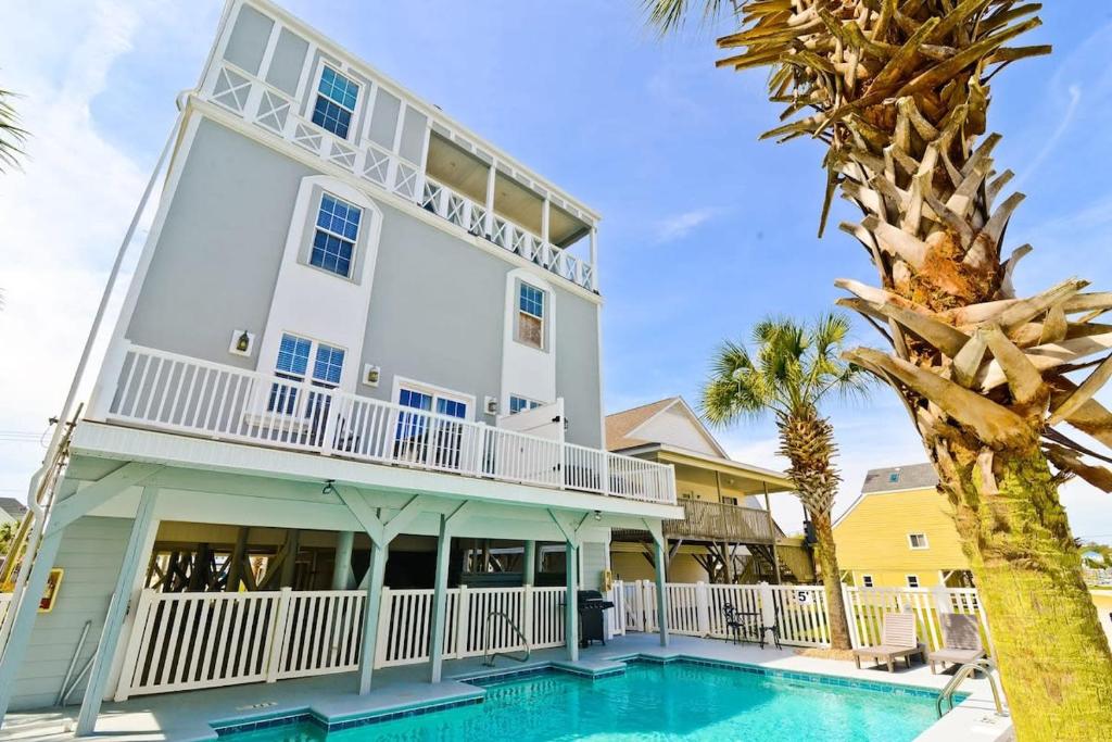 une grande maison blanche avec une piscine et des palmiers dans l'établissement Tropical Rays Huge Cherry Grove House w Pool, à Myrtle Beach