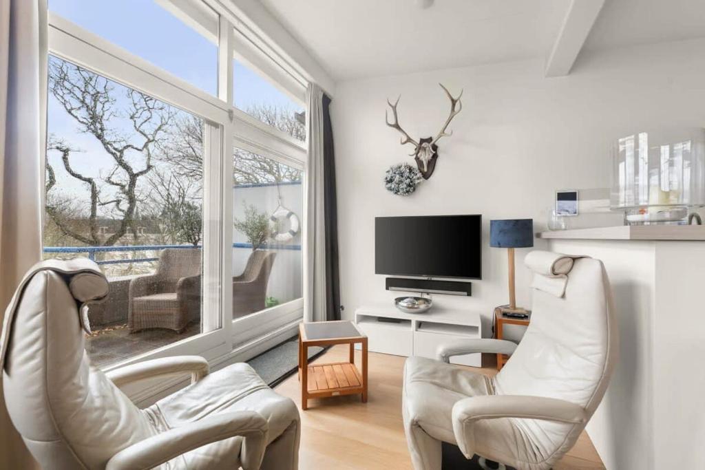 een woonkamer met witte stoelen en een groot raam bij Hello Zeeland - Appartement Loverendale 38 in Domburg