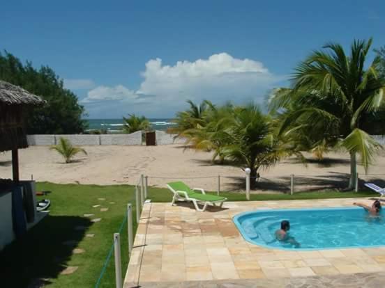 a person in a swimming pool next to a beach at Pousada Recanto dos Coqueiros in Barra do Cunhau