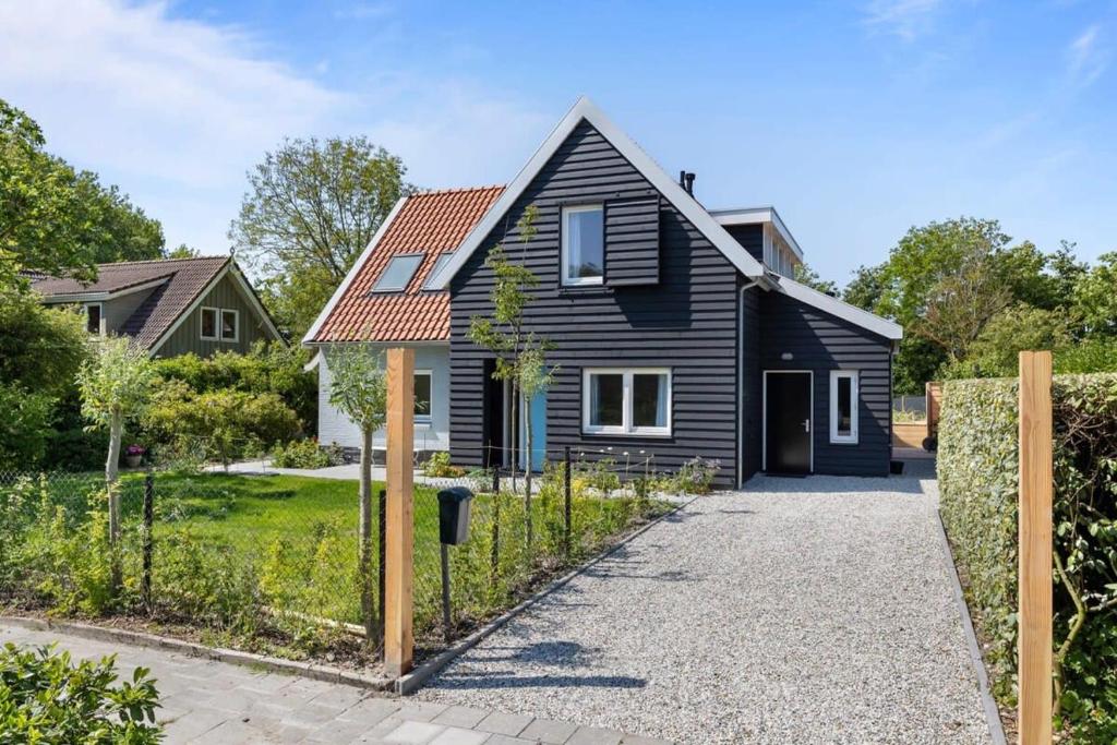 uma casa preta com um telhado vermelho em NEW Hello Zeeland - Vakantiehuis Jhr De Casembrootplein 19 em Domburg