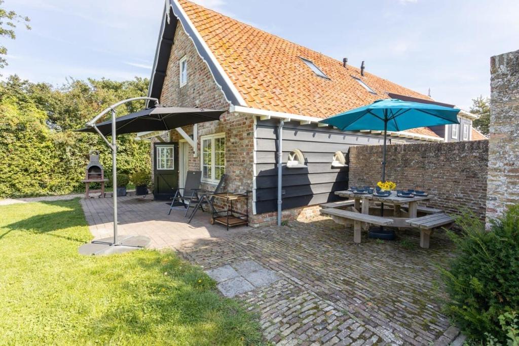 un patio con mesa y 2 sombrillas en De Grote Schuur at Buitenplaats Zeeuwse Liefde, en Westkapelle