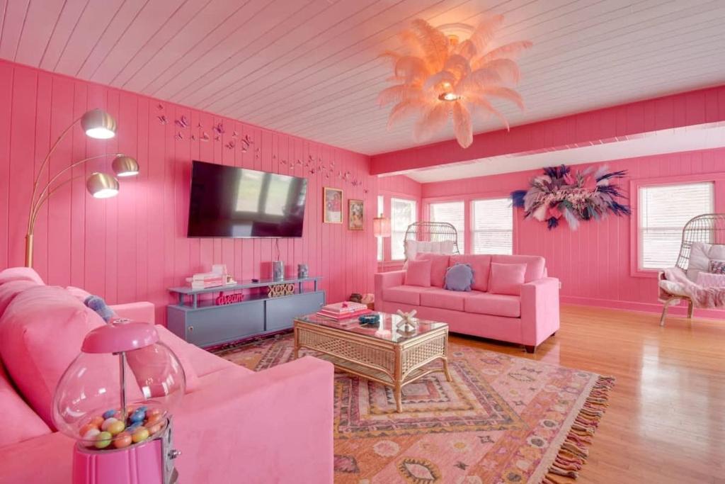 uma sala de estar cor-de-rosa com mobiliário cor-de-rosa e uma televisão em Inn the Pink One-in-a-Million Vacation Home em Myrtle Beach