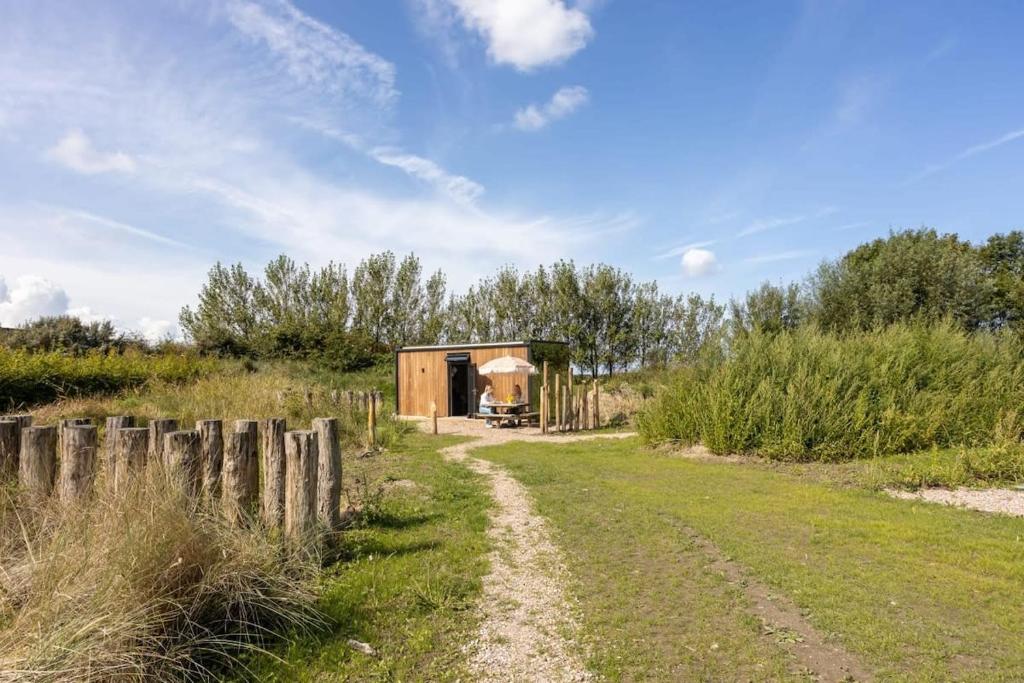 a small building in a field with a dirt road at ÖÖD Sunset at Buitenplaats Zeeuwse Liefde in Westkapelle