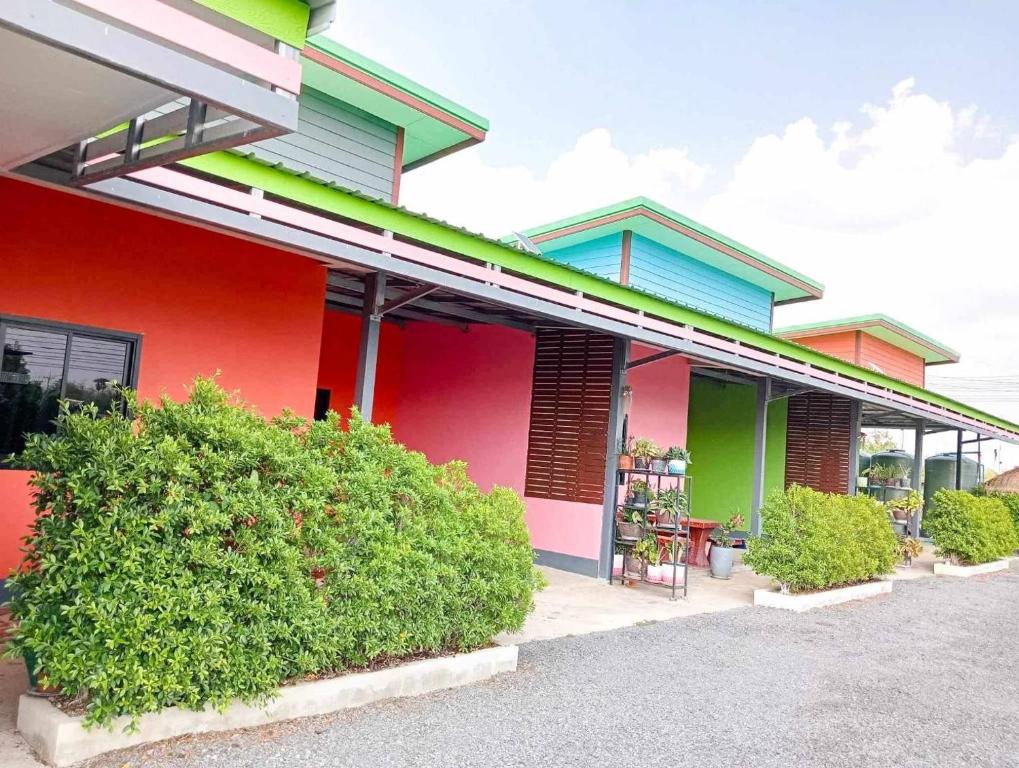 een kleurrijk gebouw met struiken ervoor bij Manee House - บ้านมณี in Buriram