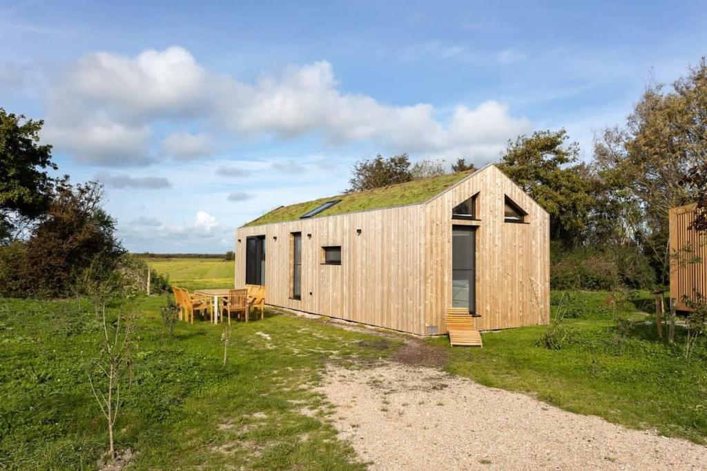 un granero de madera con techo de hierba en un campo en Hello Zeeland - Zeeuwse Liefde Tiny House 7 en Westkapelle