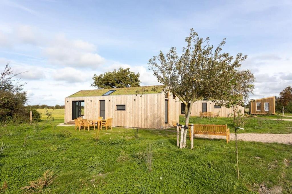 a shed with a table and a tree in a field at Hello Zeeland - Zeeuwse Liefde Tiny House 8 in Westkapelle