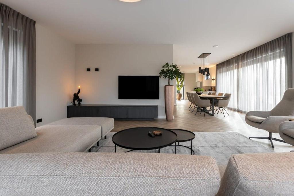 a living room with a couch and a tv at Hello Zeeland - Huisje aan de Duinen in Zoutelande