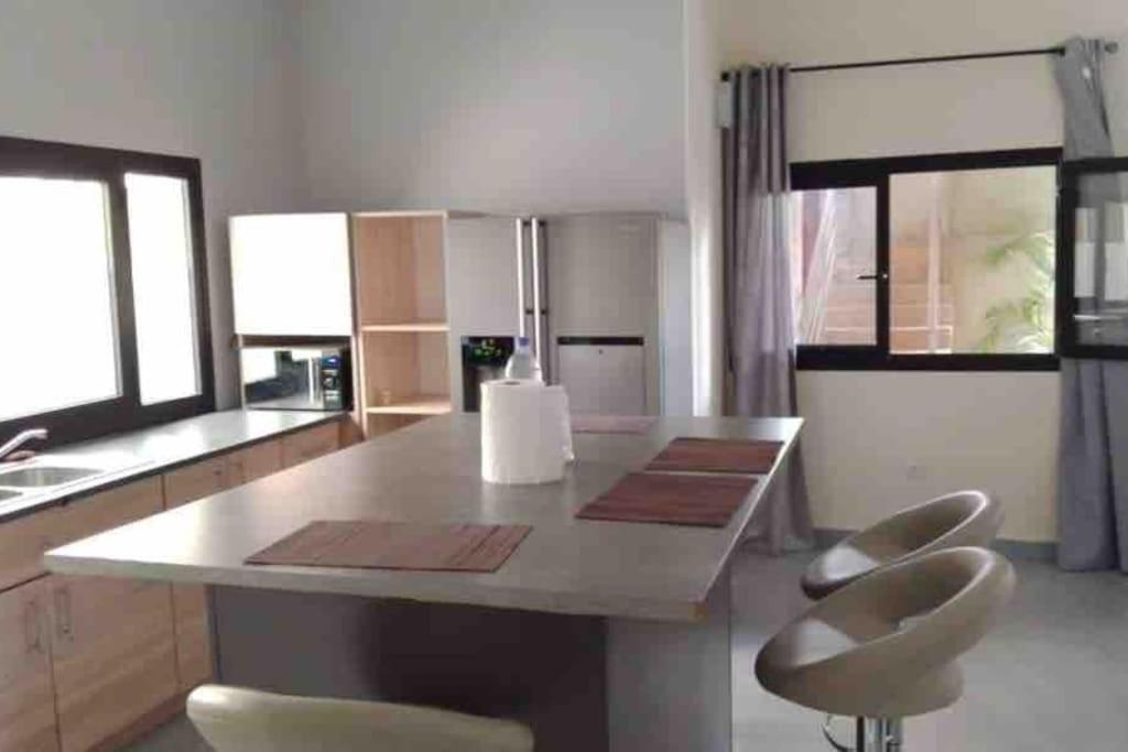 a kitchen with a large island with two stools at TANIA GUESTHOUSE in Lomé