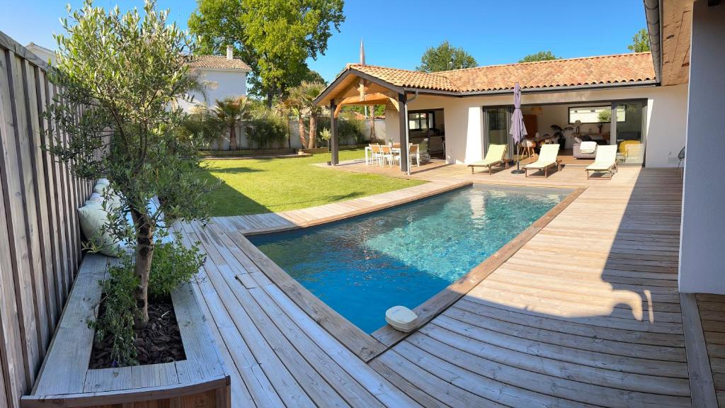 einen Hinterhof mit einem Pool und einer Holzterrasse in der Unterkunft Villa bassin Arcachon Gujan-Mestras in Gujan-Mestras