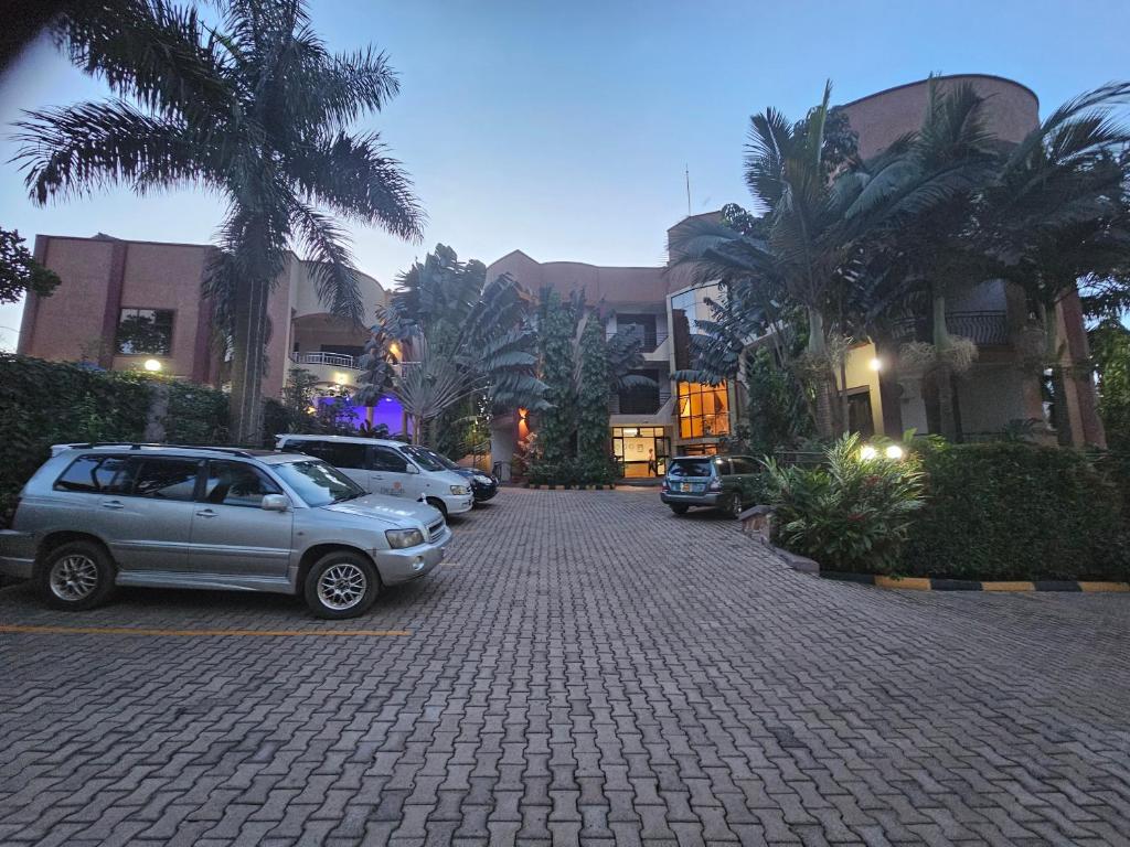 a parking lot with cars parked in front of buildings at Excelsis Garden Hotels - Kampala in Kampala