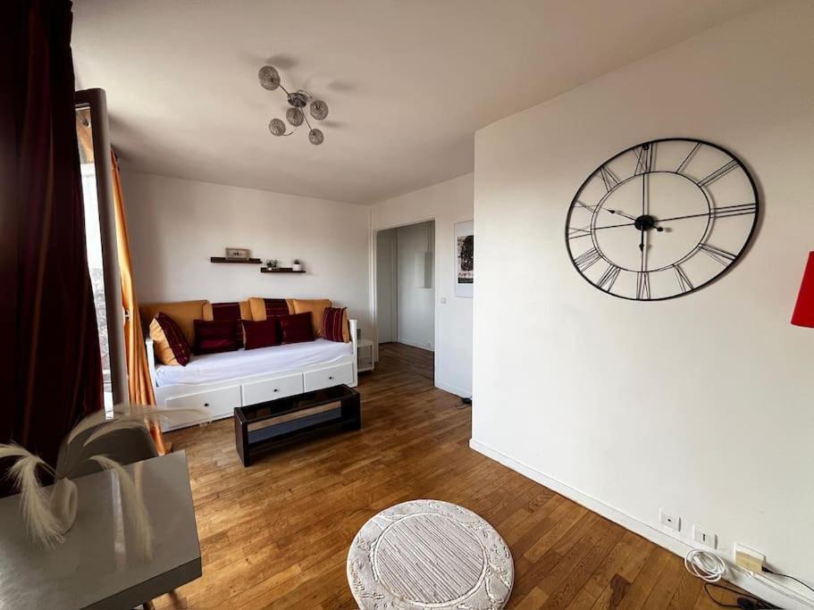 ein Wohnzimmer mit einer großen Uhr an der Wand in der Unterkunft 2p : Vue sur les toits de Paris in Les Lilas