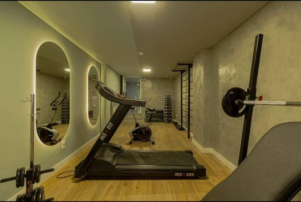 uma sala de fitness com uma passadeira e um ginásio em Loft aconchegante na melhor localização de BH em Belo Horizonte