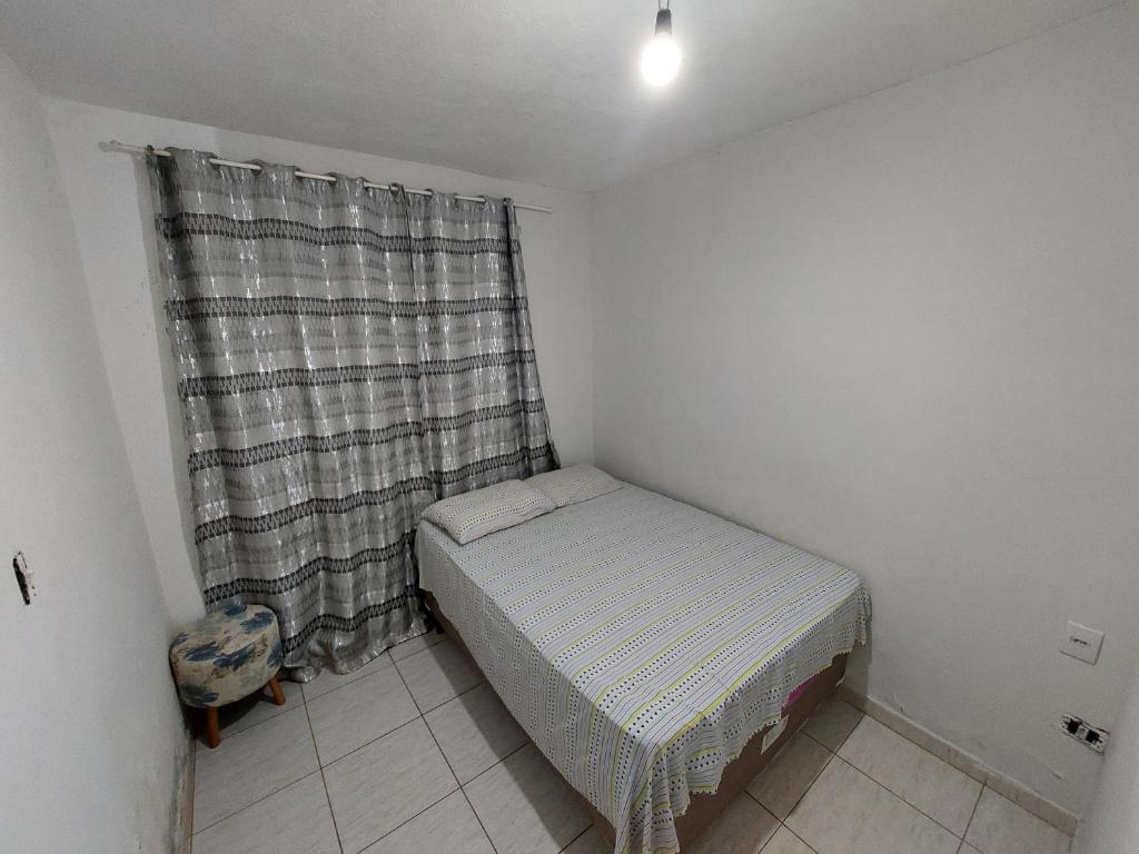 a small bedroom with a bed and a curtain at Quarto disponível para temporada da Agrishow in Ribeirão Preto