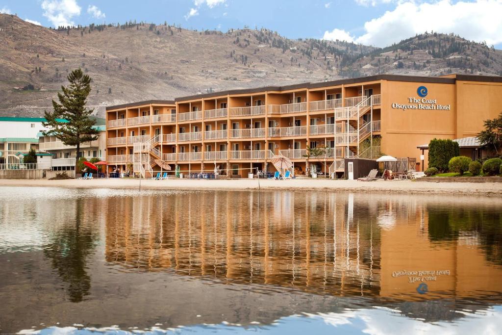 a hotel with its reflection in a body of water at Coast Osoyoos Beach Hotel in Osoyoos