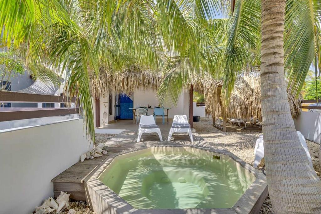 a hot tub under a palm tree in a yard at Villa Azul II in Belnem in Kralendijk