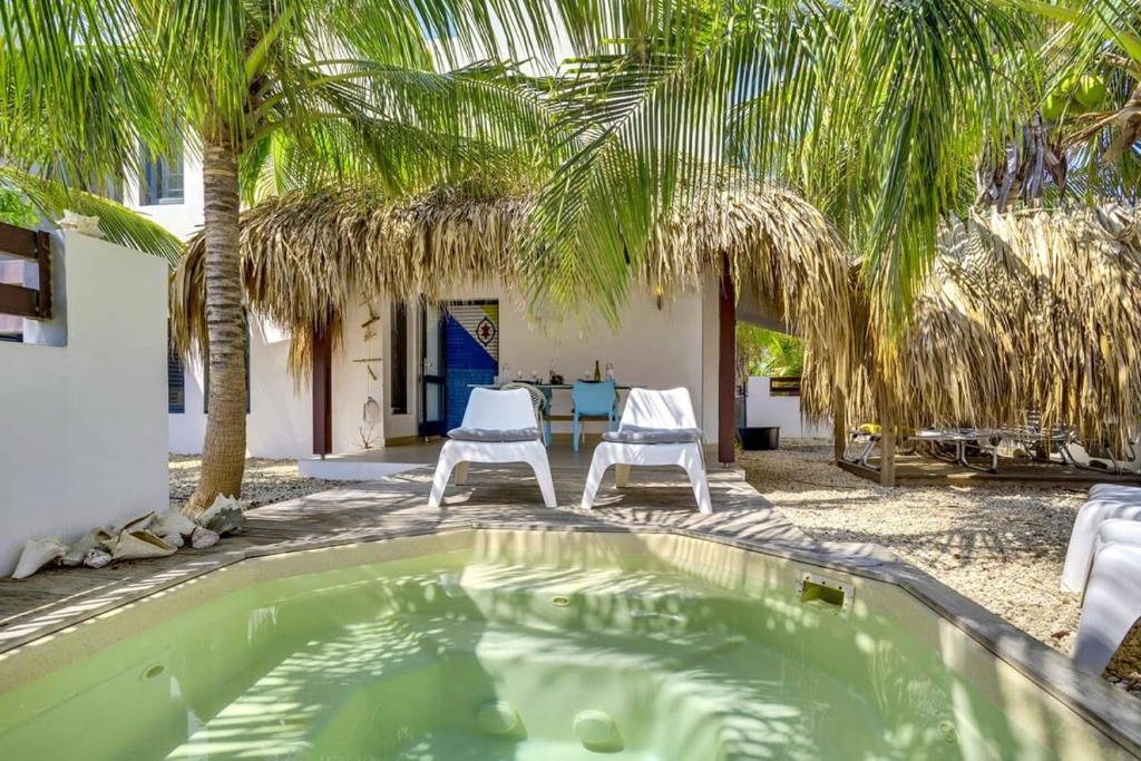 uma piscina com duas cadeiras e palmeiras em Villa Azul I in Belnem em Kralendijk