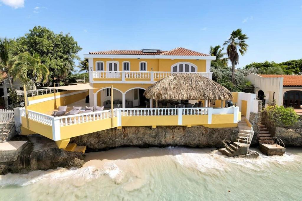 ein gelbes Haus am Ufer des Wassers in der Unterkunft Oceanfront villa Casa Mar Azul in Kralendijk