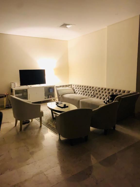 sala de estar con sofá, sillas y TV en Arsaad villa apparments, en ‘Ūd al Bayḑāʼ