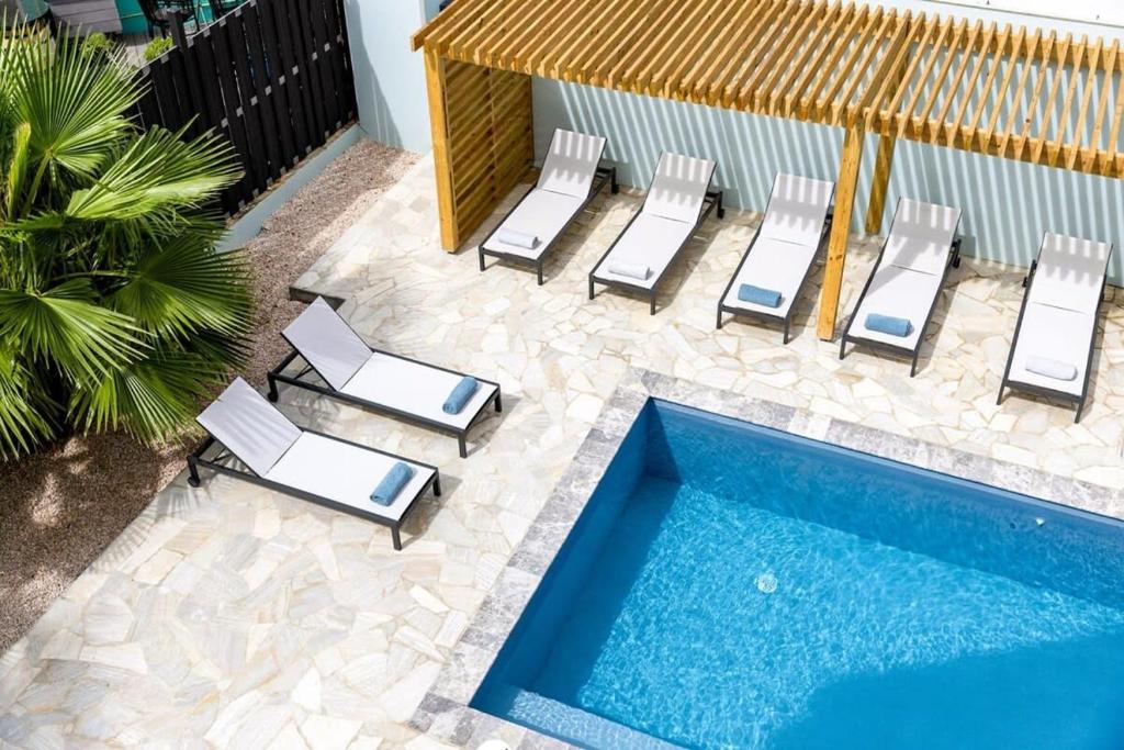 a group of lounge chairs and a swimming pool at Liv Inn Bonaire with Pool and Nice Cooling Winds in Kralendijk