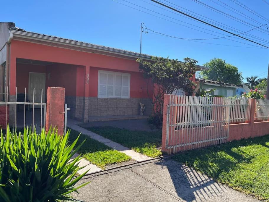 een rood huis met een wit hek ervoor bij Casa Girassol in Praia Grande