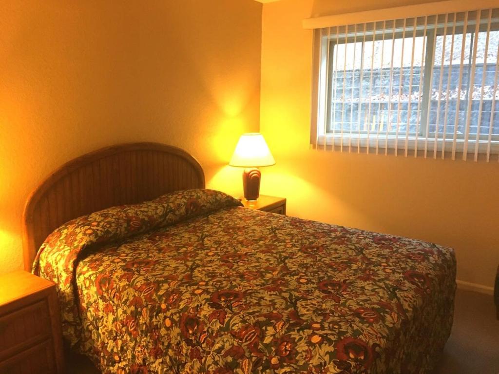 a bedroom with a bed and a lamp and a window at Condo with Heated Pool and Indoor Hot Tub and Shuffleboard at Lake Ozarks in Osage Beach
