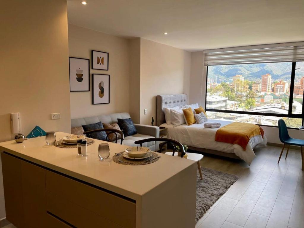 een keuken en een woonkamer met een bank en een bed bij Excepcional loft cerca del Parque La 93 in Bogota