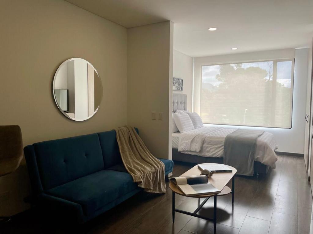 sala de estar con sofá, cama y espejo en Serenity Near Country Club - Loft Retreat, en Bogotá