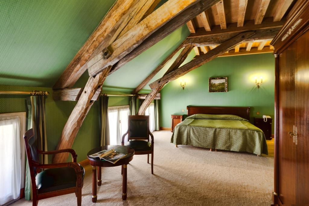 ein Schlafzimmer mit grünen Wänden sowie einem Bett und Stühlen in der Unterkunft Hotel Belle Epoque in Beaune