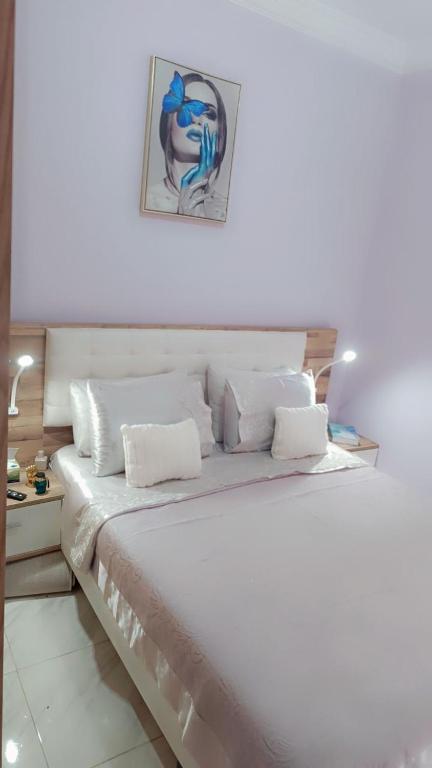 un letto bianco con cuscini bianchi e un dipinto sul muro di Appartement Basatine a Fes