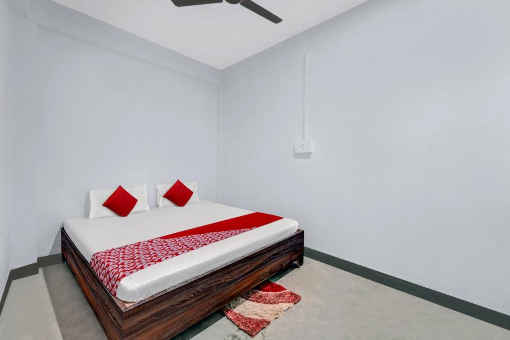 a bed with red pillows in a white room at OYO Flagship YUVRAJ Hotel in Patna