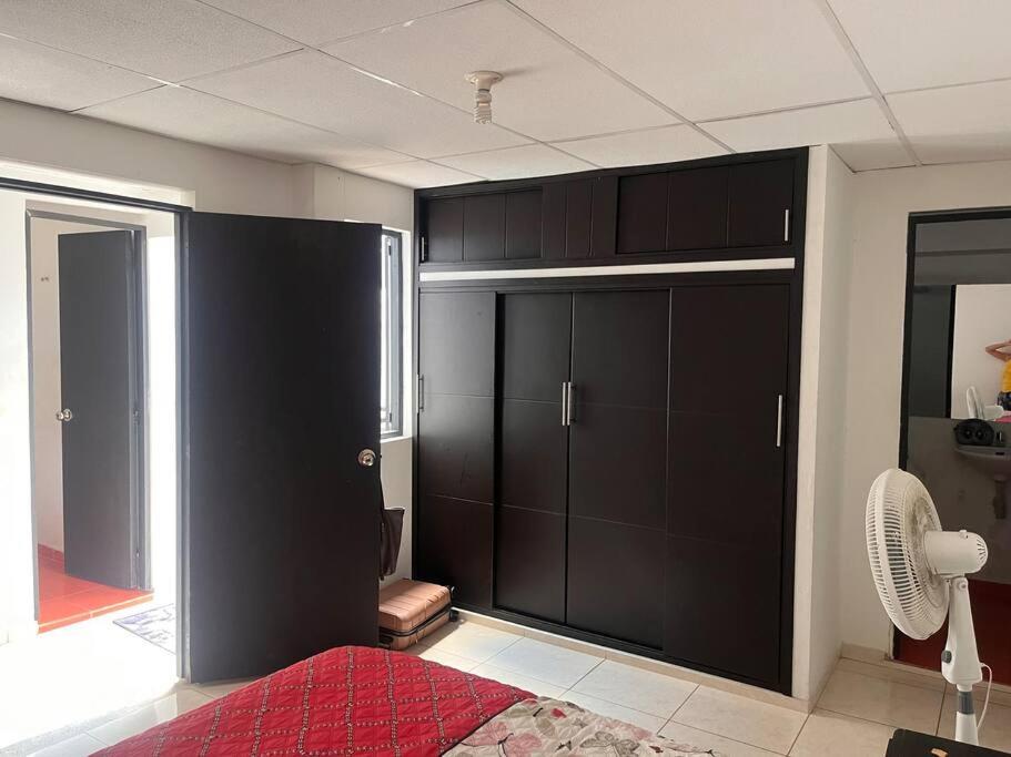 a bedroom with black cupboards and a fan at Un sitio súper familiar y tranquilo in Villavicencio