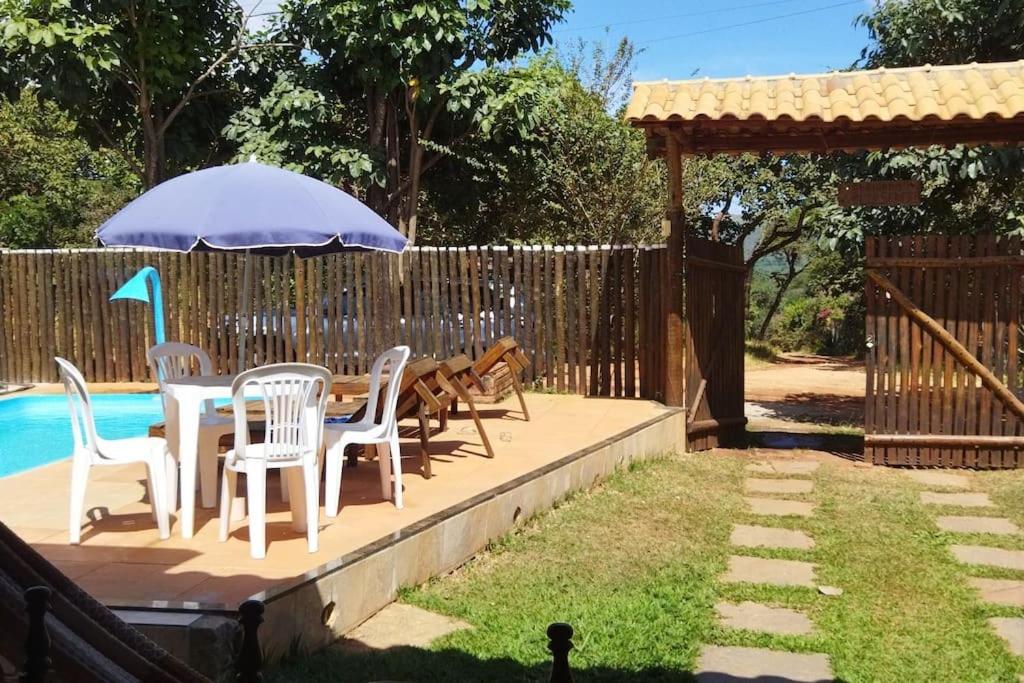 une terrasse avec une table, des chaises et un parasol dans l'établissement Casa das orquídeas, à Santana do Riacho